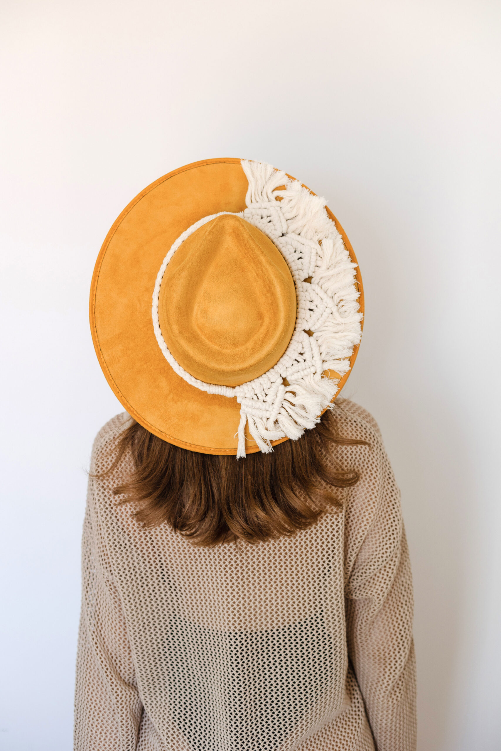A yellow colored hat made in Mexico made from synthetic suede back with an ivory colored macrame hat accessory